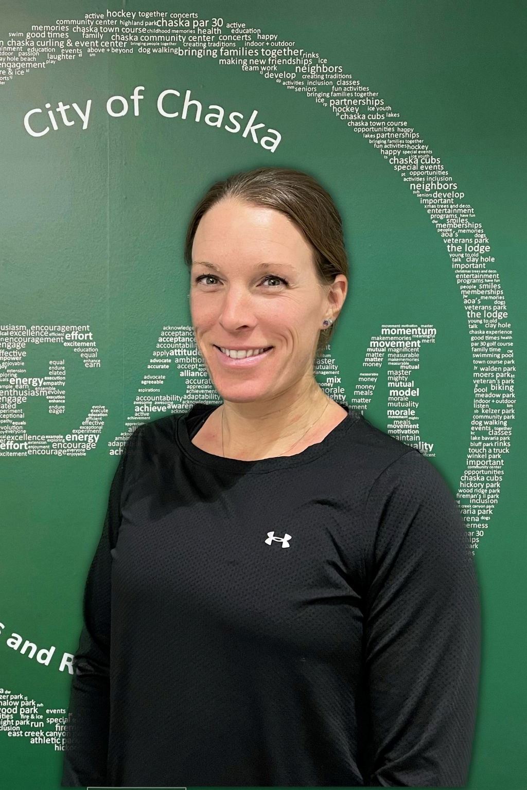 Personal Trainer Kari Hilgert in black shirt standing in front of green TEAM sign